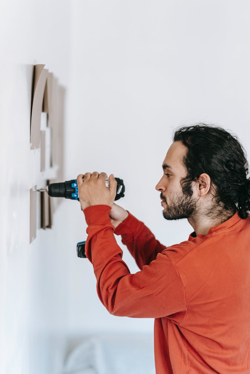 man in red long sleeve shirt holding a drilling tool
